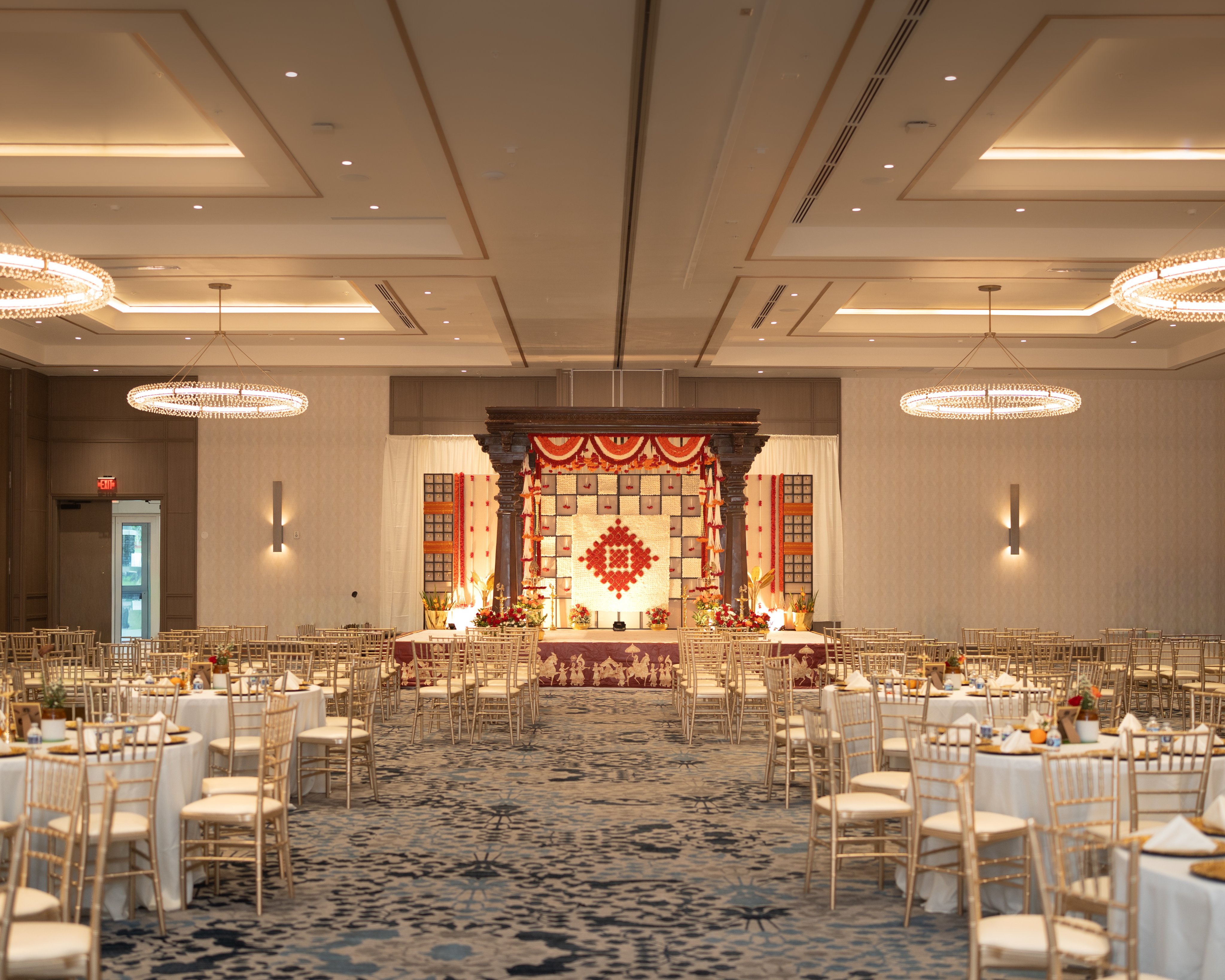 Grand wedding mandap with red florals and dark carved pillars