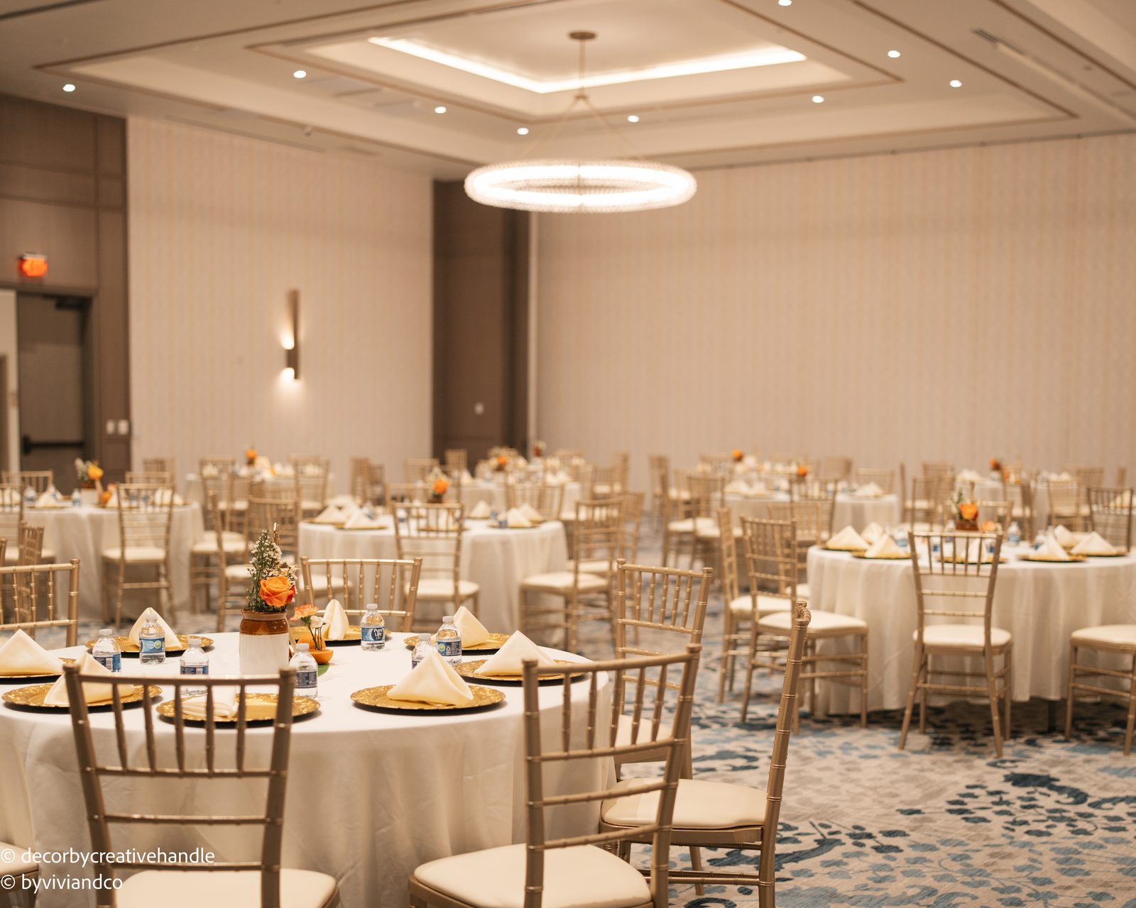 Wide reception room with gold chairs and orange floral table details