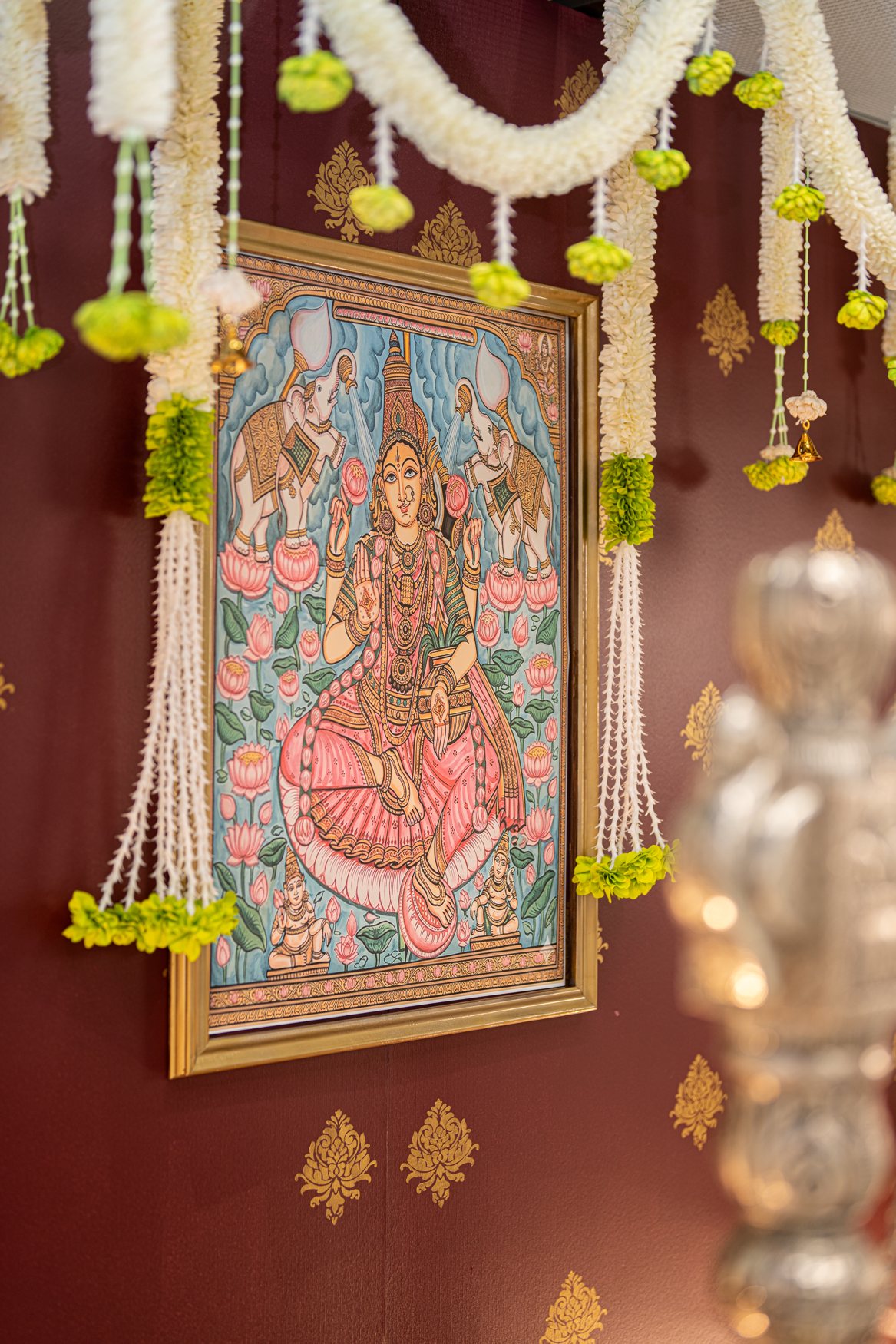 Framed deity artwork adorned with flower garlands